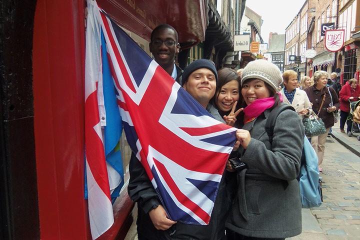 Three students holding a UK flag