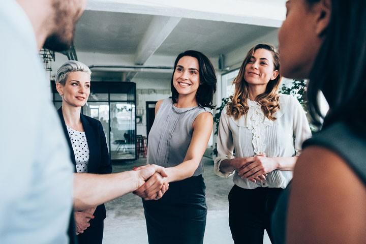 A person shaking another person's hand in a group of five